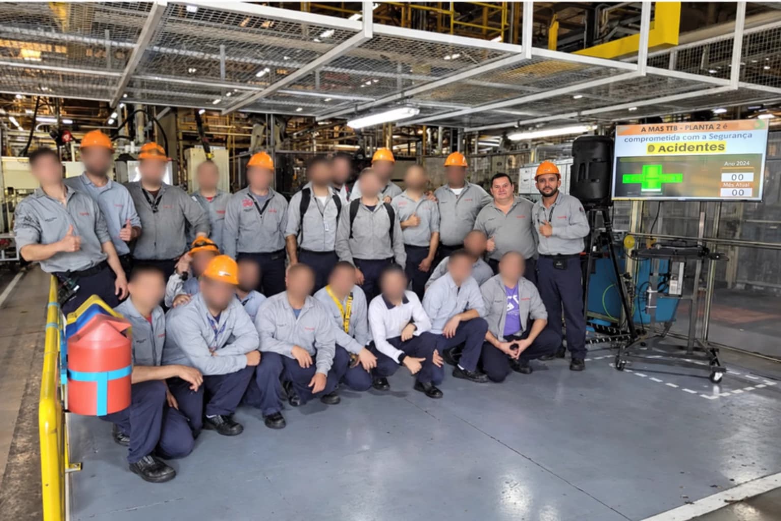 Equipe reunida em uma área produtiva com painel de segurança