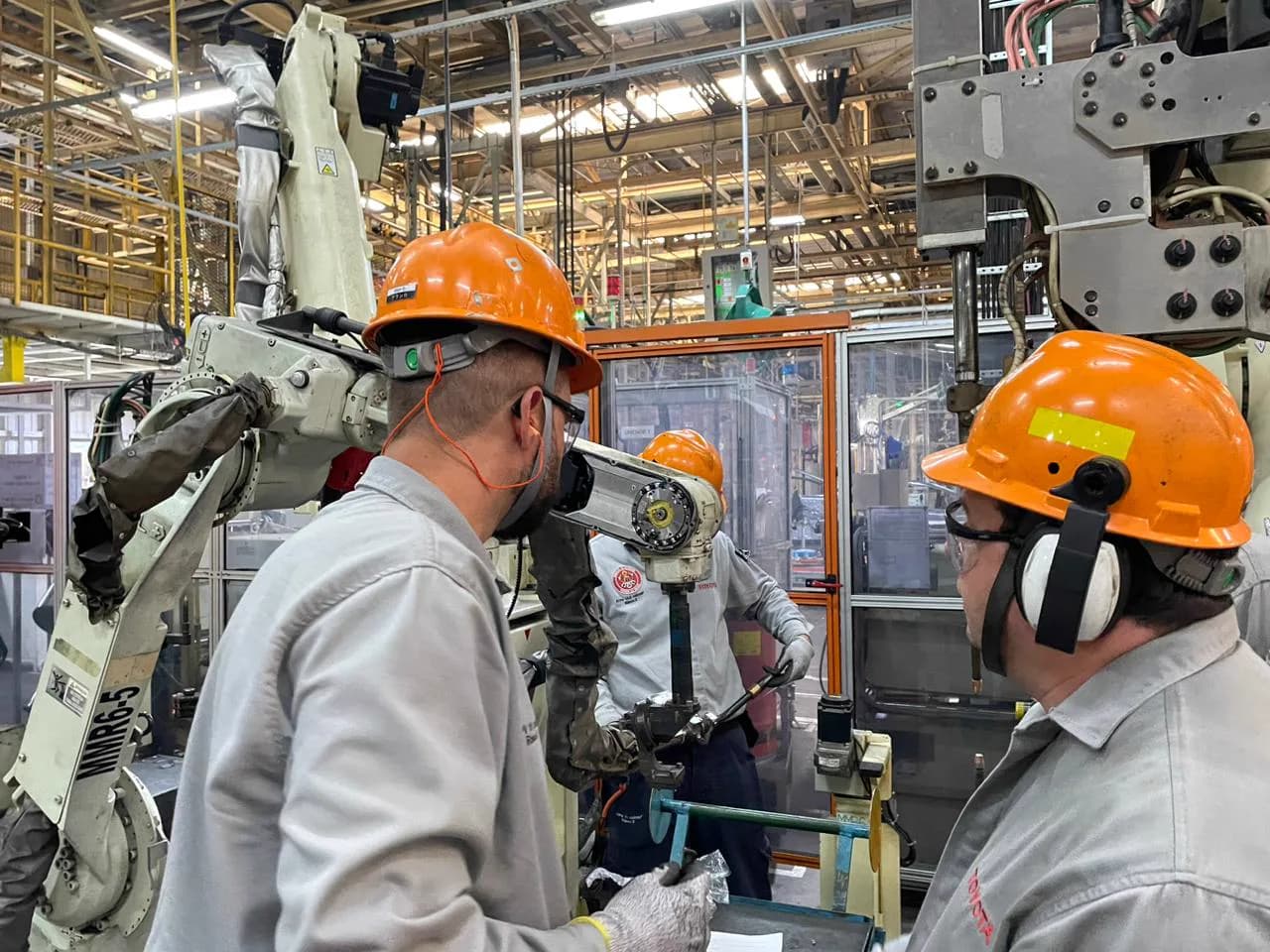 Equipe observando um equipamento automatizado na área produtiva