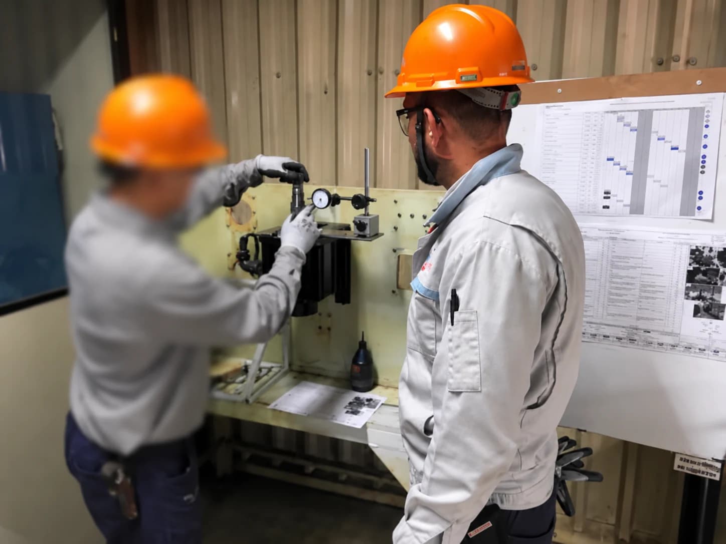 Profissionais verificando um equipamento com instrumento de medição